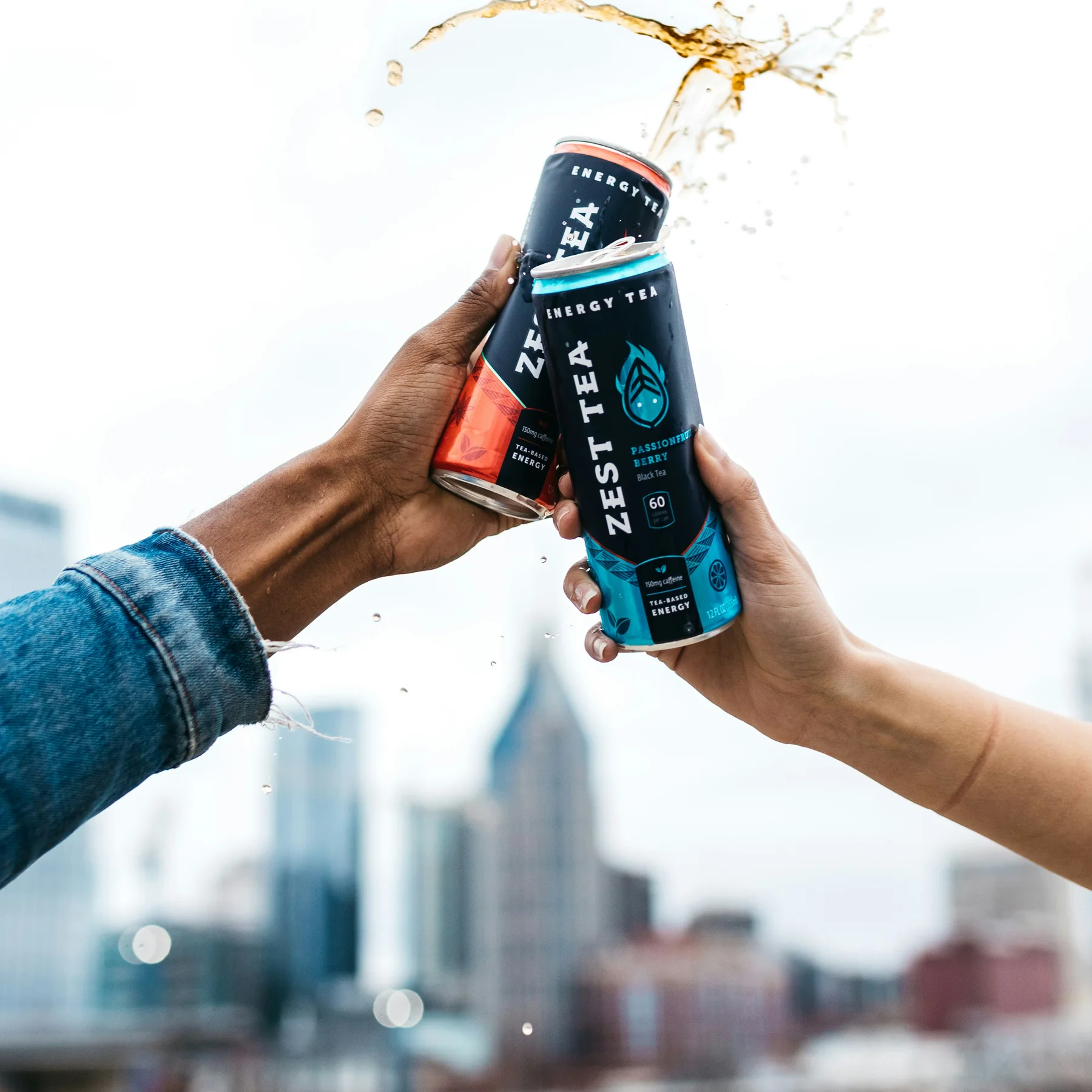 Zest Tea ready-to-drink energy cans raised in a celebratory toast